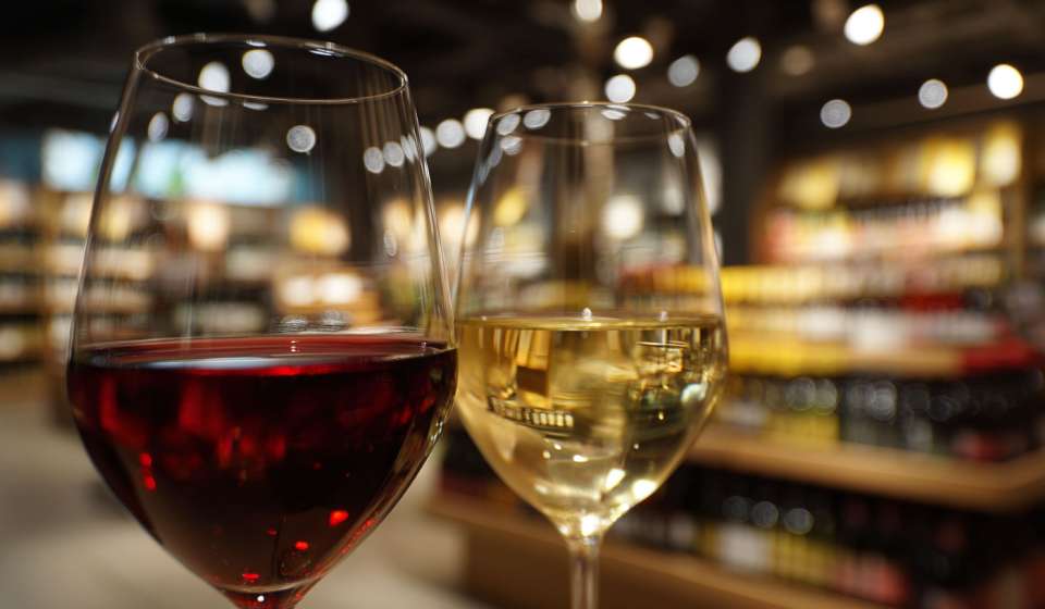 Ett glass rött och ett glas vitt vin framför Systembolaget butik
